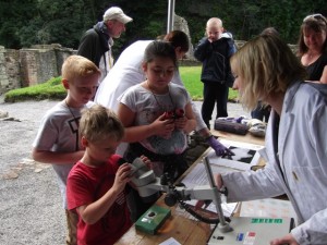 Sara shows some young visitors how we look at objects using microscopes at a National Trust Open Day. Photograph courtesy of the National Trust.