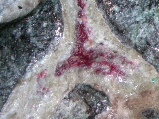 A higher magnification closeup of a triangular deposit of the same dark red material.
