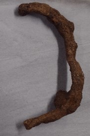 A large, roughly 'C' shaped metal bar resembling a handle, covered in brown lumpy corrosion.