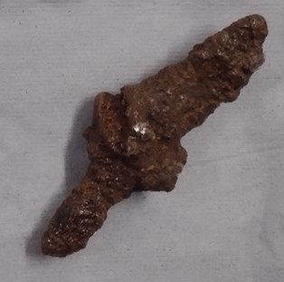 An object resembling a small knife covered in lumpy dark brown corrosion.