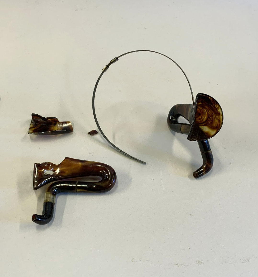 Image shoes a hearing cornet broken into four pieces.
