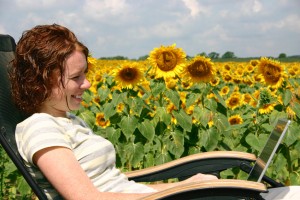 A young lady working on her laptop out by the sunflowers