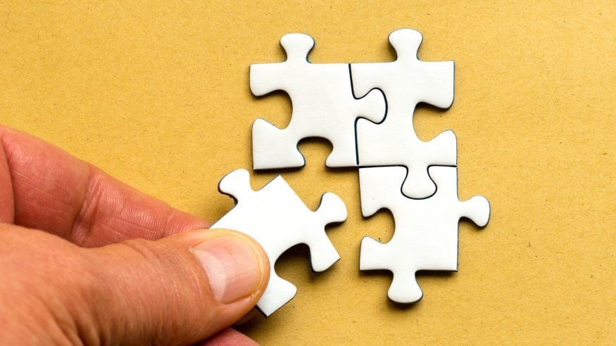 Hand placing jigsaw pieces together