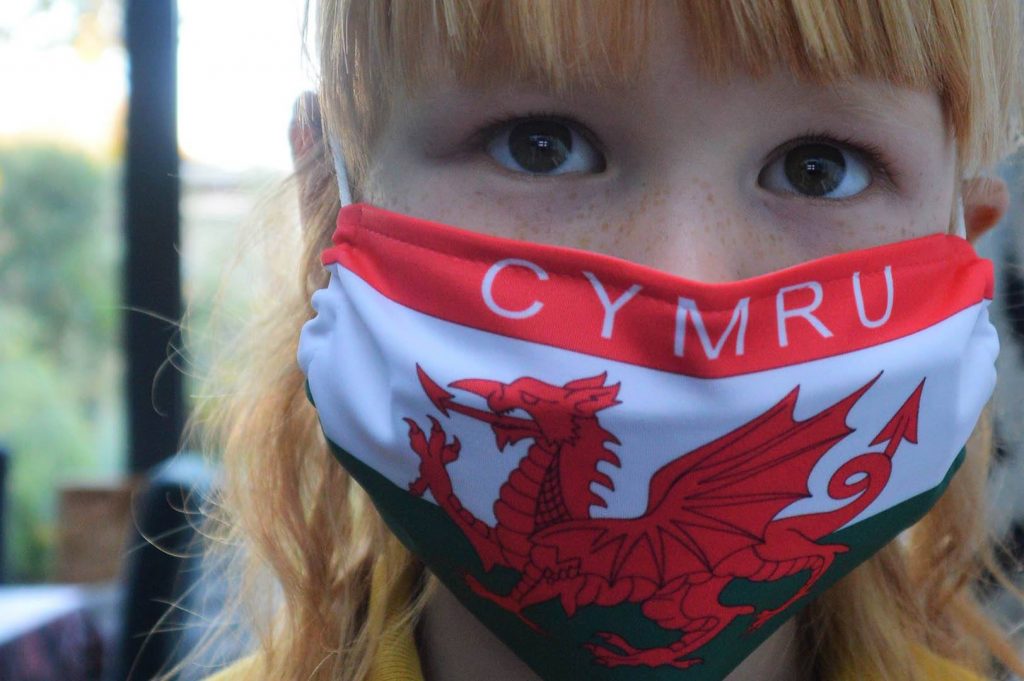 Girl wearing a mask bearing the Welsh flag.