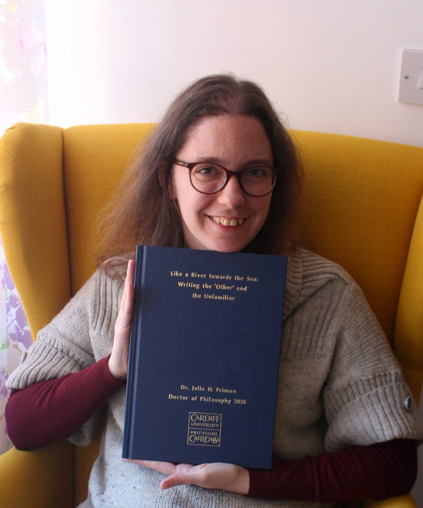 Julie showing her completed, bound thesis to the camera.