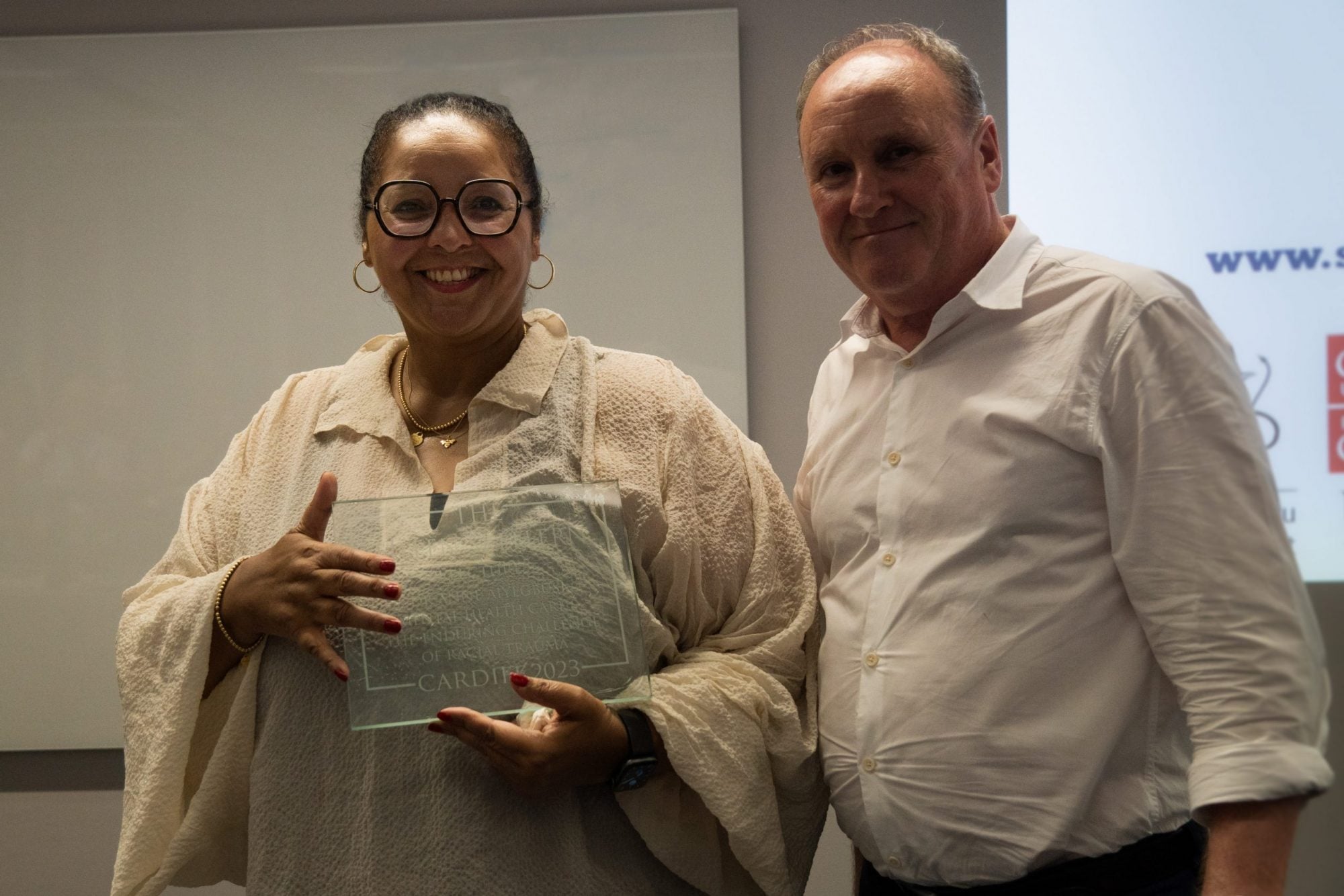 A woman holding a plaque given to her by the man standing next to her