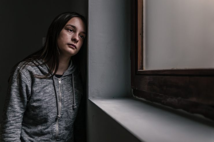 Sad and contemplative young woman by a window.