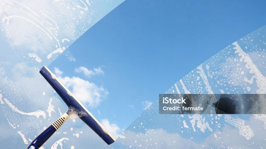 Rubber squeegee cleans a soaped window and clears a stripe of blue sky with clouds, concept for tranparency or spring cleaning, copy space in the background