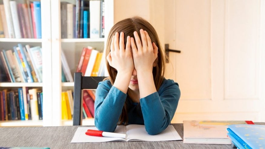 A young girl at her desk, head in hands