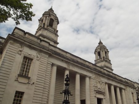 Cardiff City Hall building facade set against the backdrop of a cloudy sky.