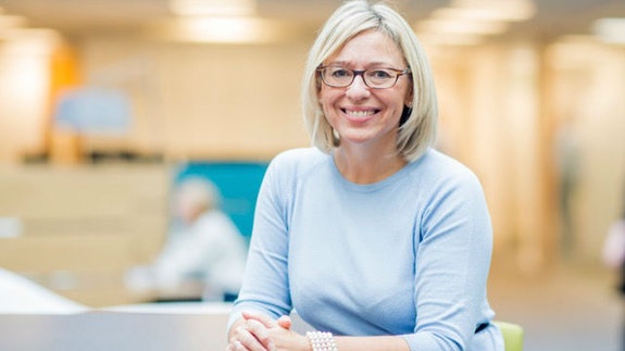 Claire Morgan. Female wearing glasses and a blue jumper smiling at camera.