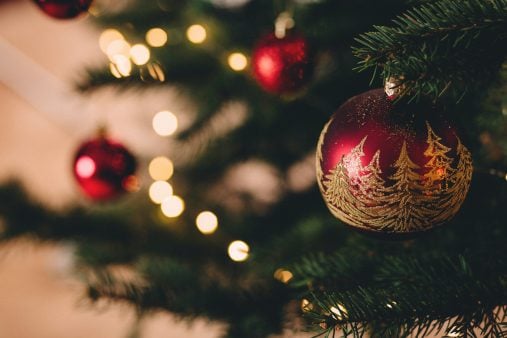 a red and gold bauble in focus on a Christmas tree