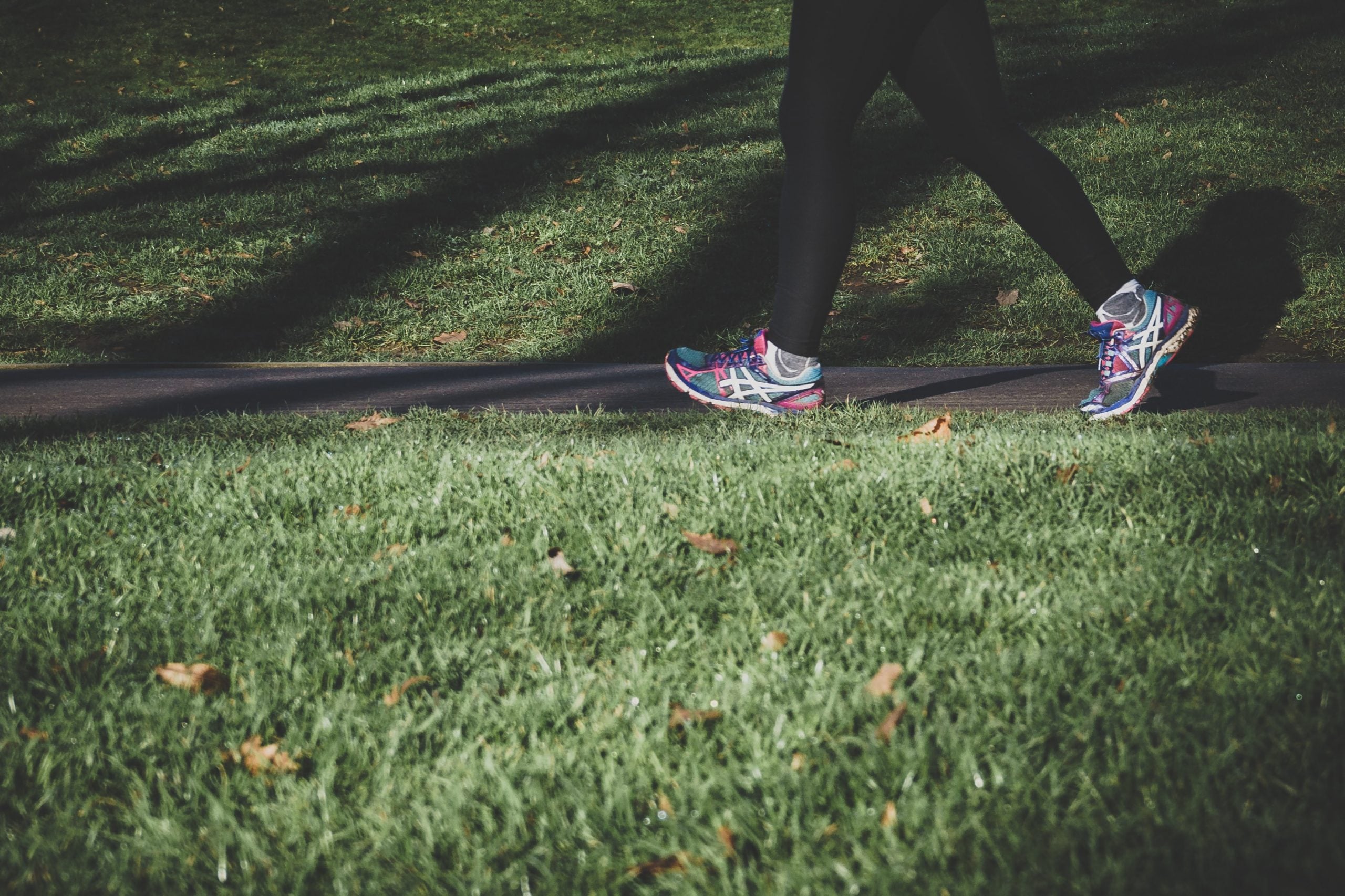 A close up shot of someone's feet walking in a park