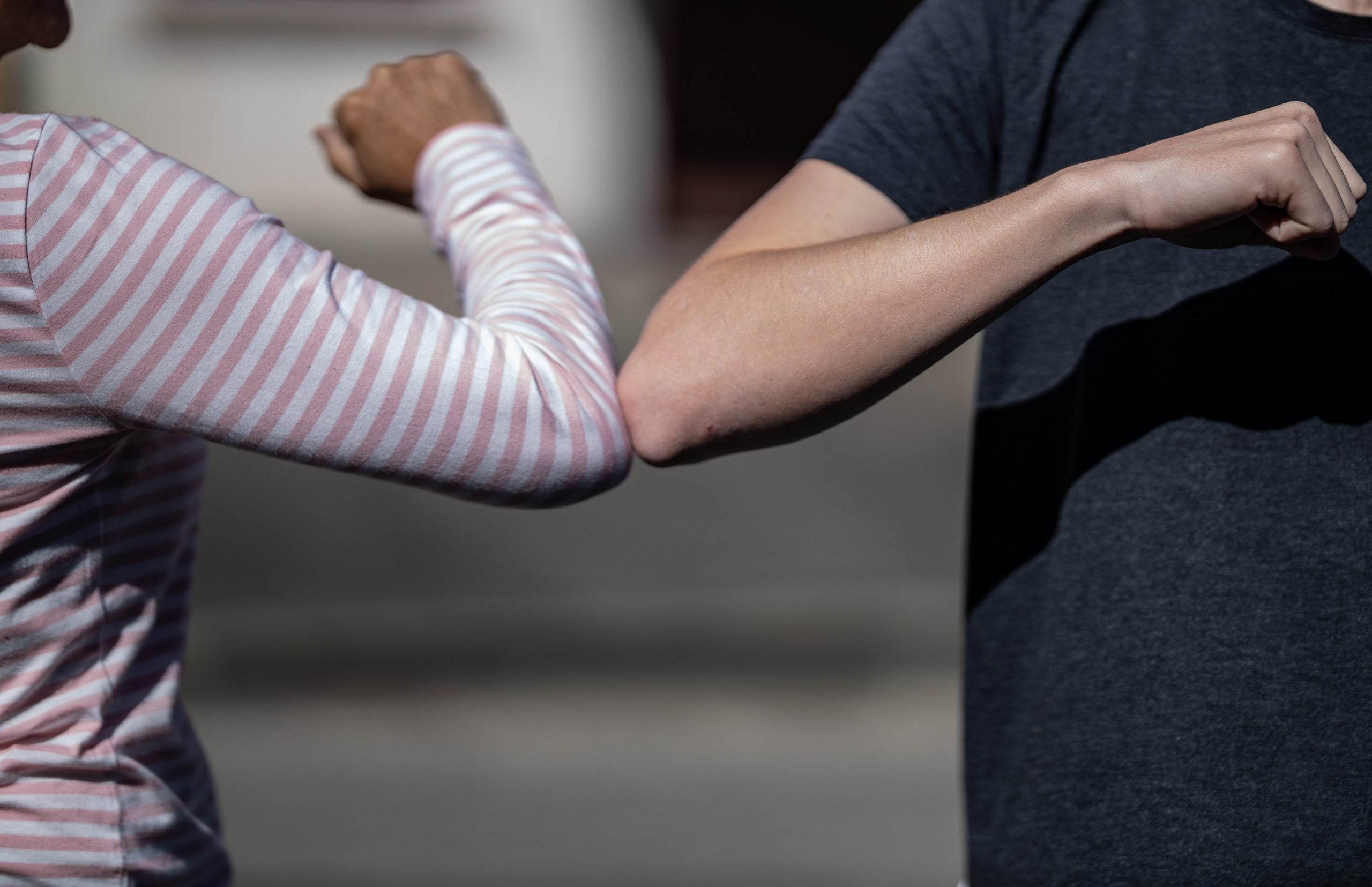 two people greet one another by bumping elbows
