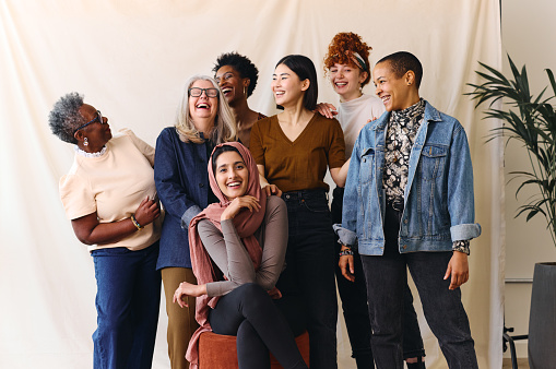 a diverse group of women of mixed ages stand in a group laughing