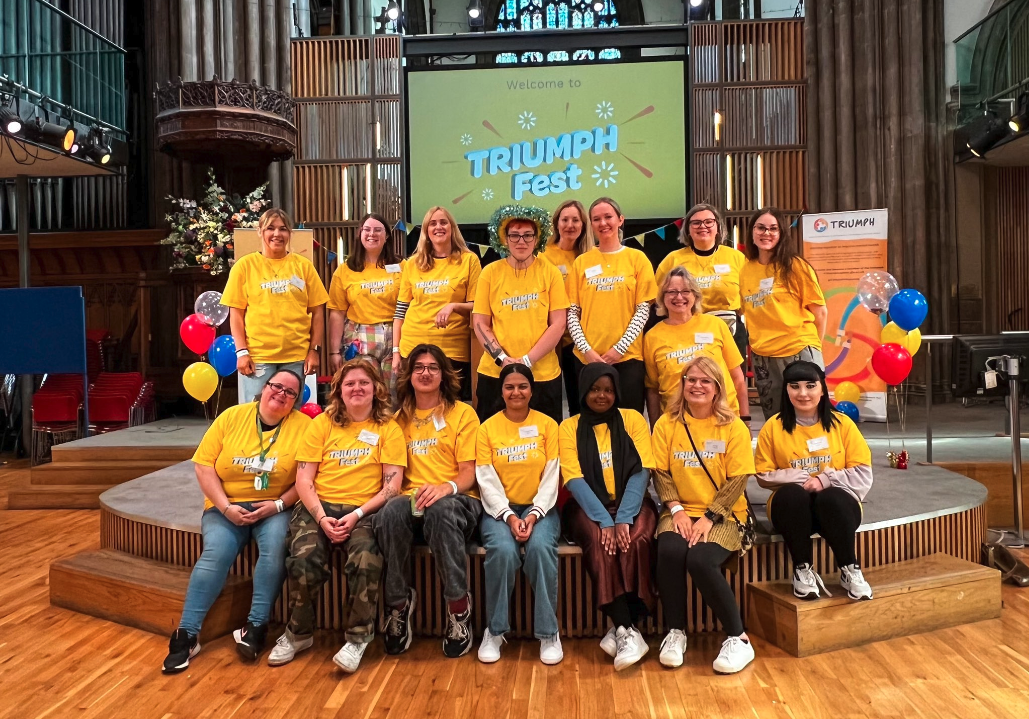 Two rows of young people in yellow tshirts on stage in a large venue